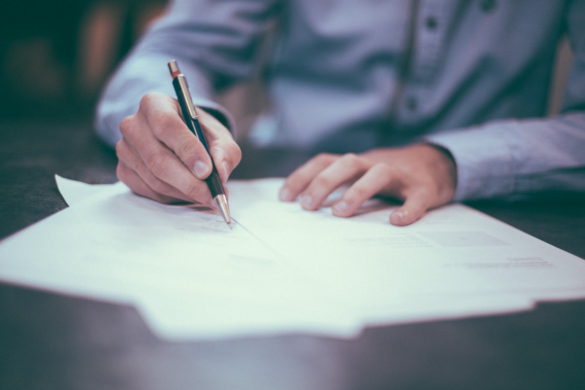 Person reviewing loan documents and a laptop with financial paperwork spread on a desk